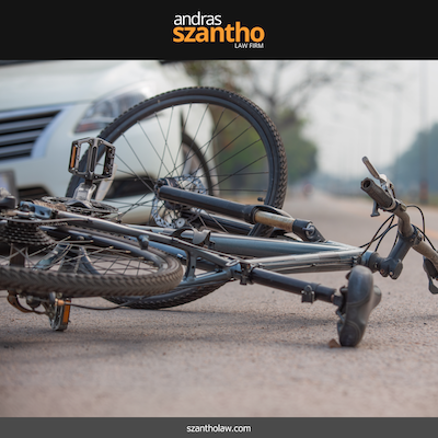 A twisted-up bike lying on the ground in front of a car after a bicycle accident in Santa Fe