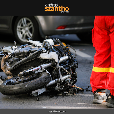 Damaged motorcycle on the ground with a responder standing nearby after an accident in Albuquerque